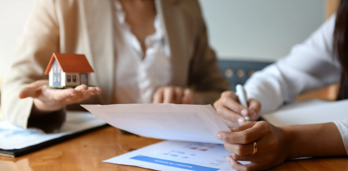 appraiser discussing property valuation worker with a model of a house on the hand showing a client